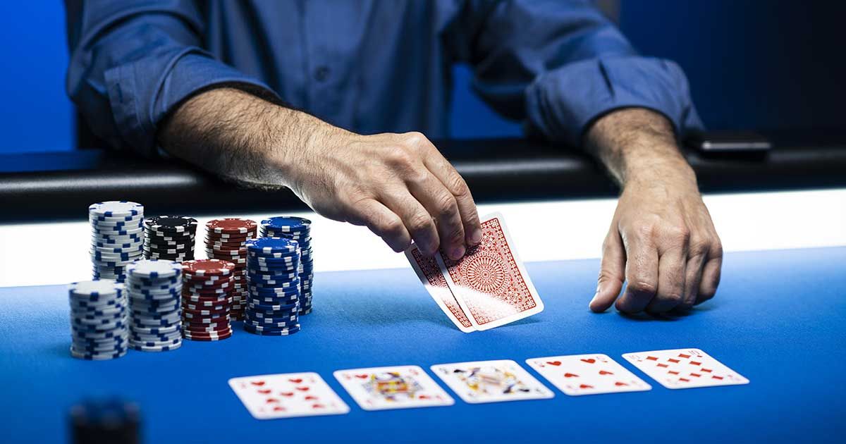 Man Looking at Poker Cards on Table