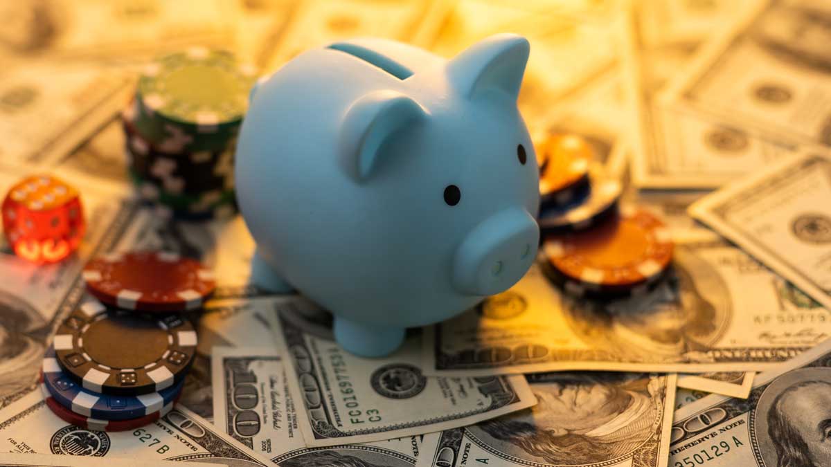 A piggy bank on a pile of cash with poker chips