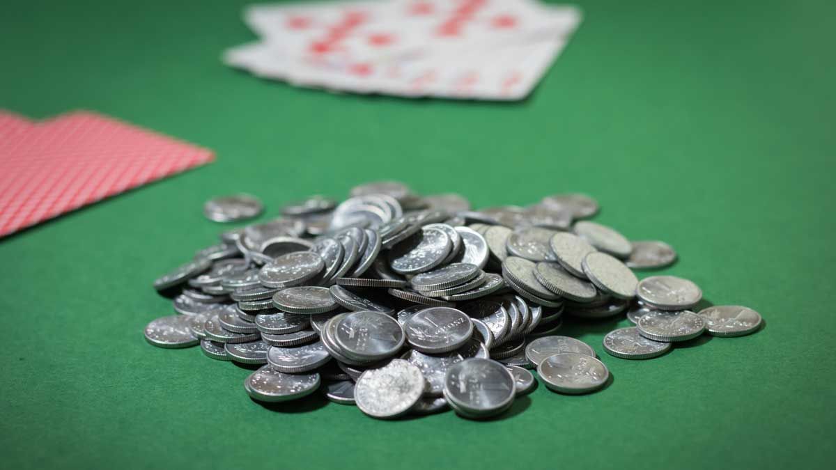 A stack of coins with playing cards on the table