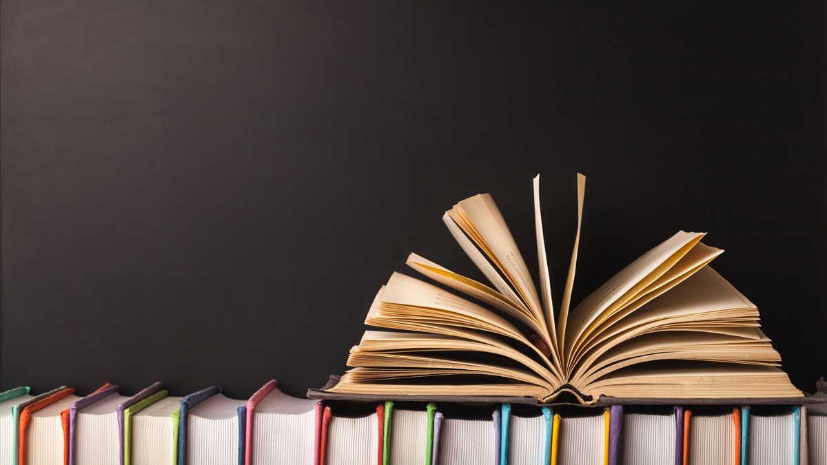 A shelf of books with one open book